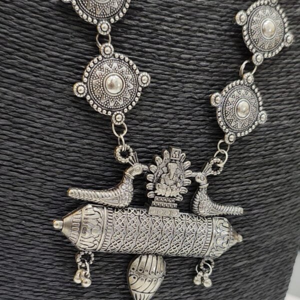 Close up of oxidised peacock pendant necklace with detailed carvings and round motif chain