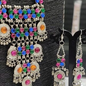 Oxidised silver tone necklace set with multicolor stones and dangling elements paired with matching earrings on display stand