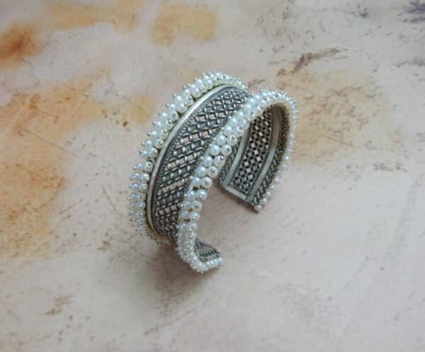 Oxidised silver jali cuff bracelet with pearl border — angled view showing full band