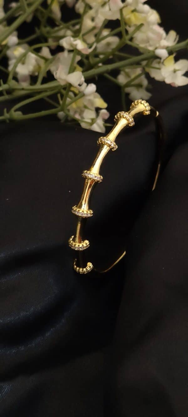 angled view of Bamboo anti tarnish kada for women in gold-toned segmented design with American diamond stones