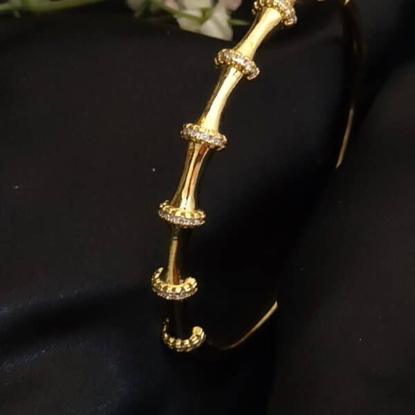 angled view of Bamboo anti tarnish kada for women in gold-toned segmented design with American diamond stones