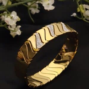 side view of a Wave anti tarnish kada for women in gold-toned diagonal wave design with American diamond stones
