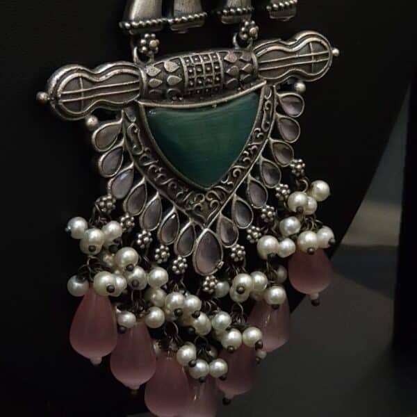 Close-up of elephant topper and green stone shield on oxidised brass pendant necklace