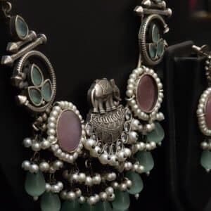 Close-up of elephant charm pendant on oxidised brass necklace with pearl tassels