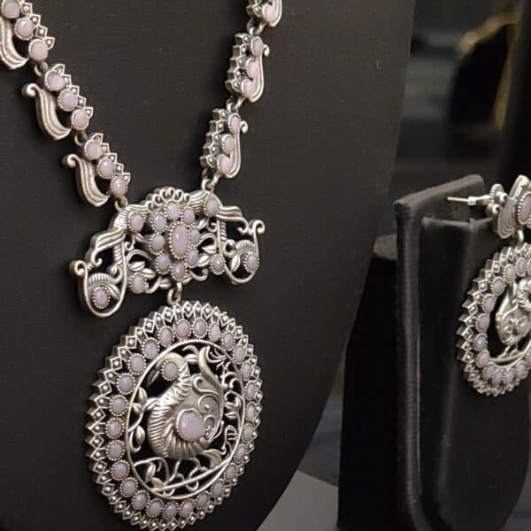 Close-up of peacock medallion pendant in oxidised brass with lavender stones