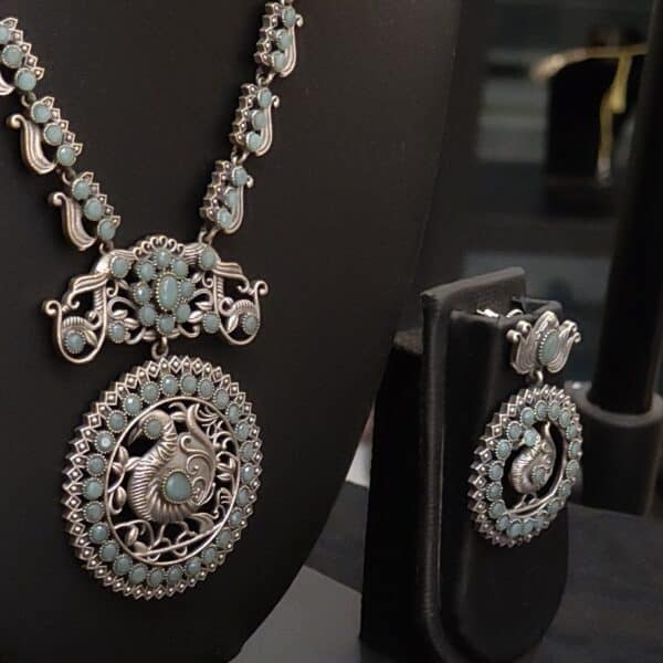 Close-up of peacock medallion pendant in oxidised brass with sea green stones